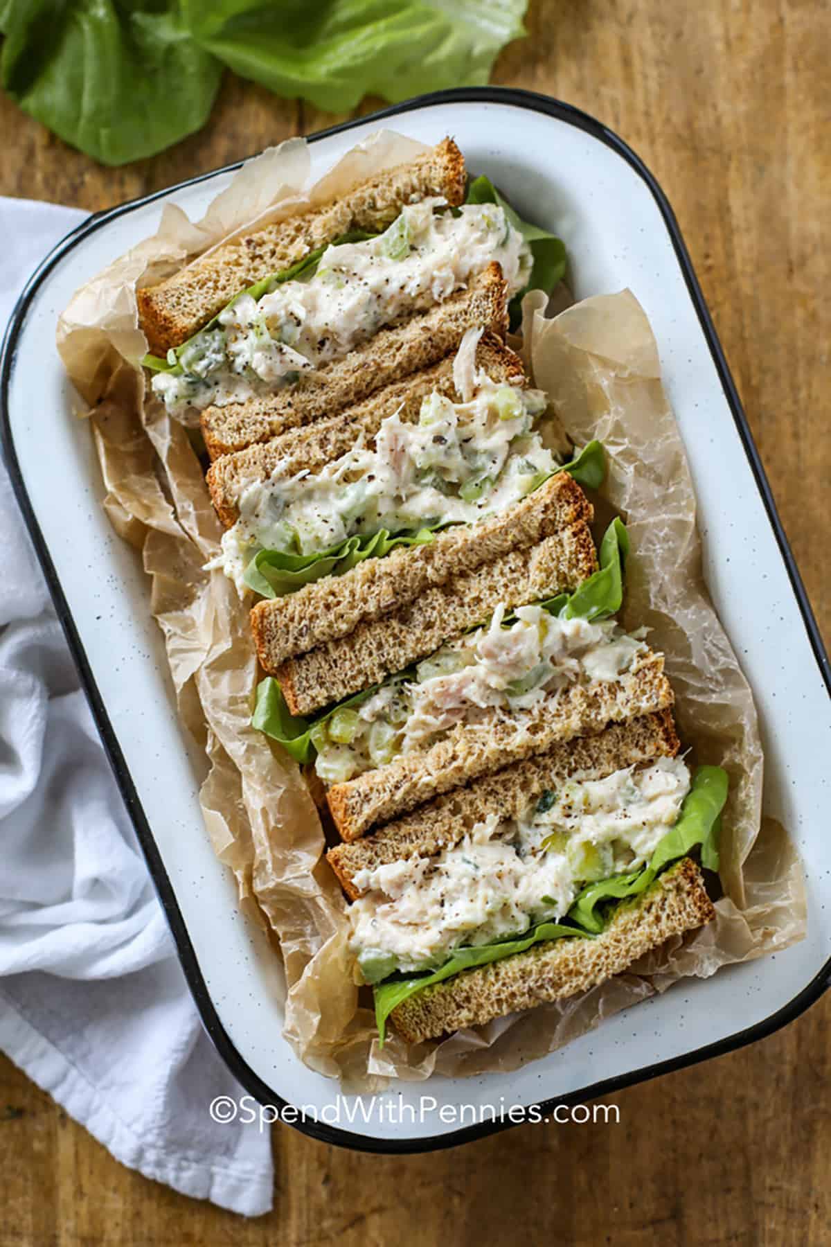 A tray holds chicken salad sandwiches on whole grain bread, layered with lettuce.