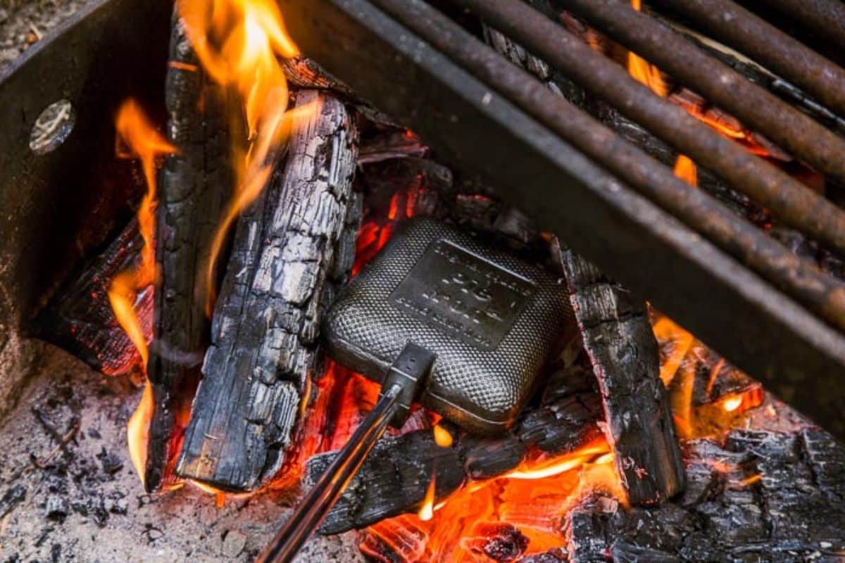 A square pie iron in a campfire.