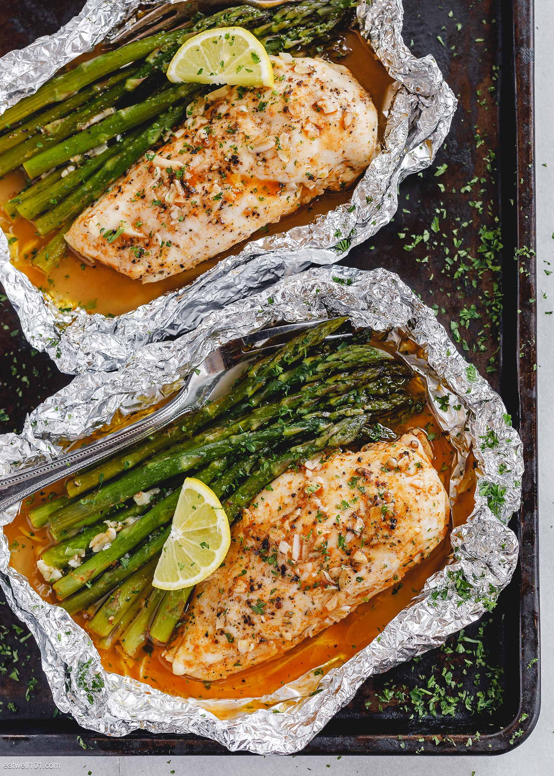 Chicken, asparagus spears, and a lemon wedge in foil.