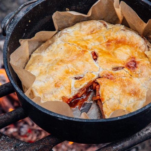 Apple pie in a Dutch oven with a slice taken out