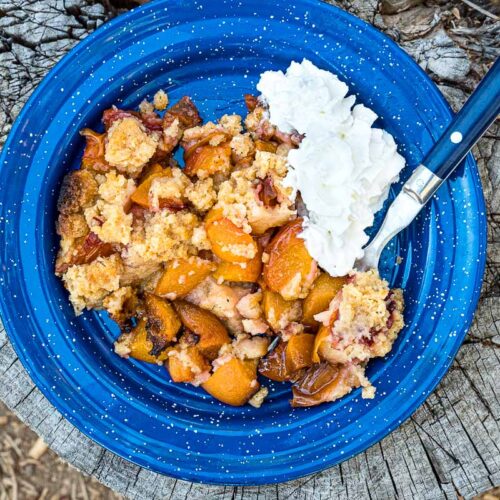 Peach cobbler and whipped cream on a blue plate