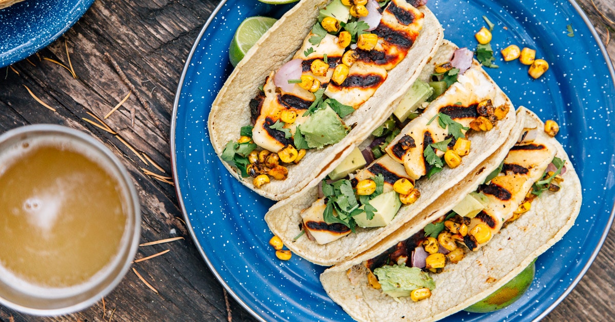 Three grilled halloumi tacos on a blue camping plate