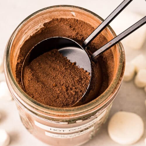 A top view of a mason jar full of hot cocoa mix with a ¼ cup measure scooping the mix out for homemade hot cocoa.