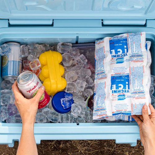 Hands reaching into a blue cooler full of ice to pick up a drink can