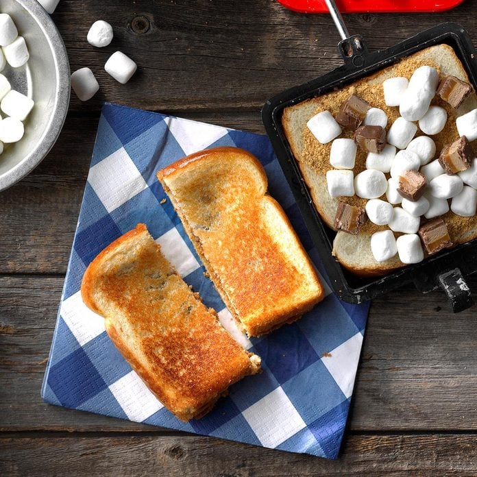 Pudgy pie filled with marshmallows and chocolate on a blue and white checkered napkin.