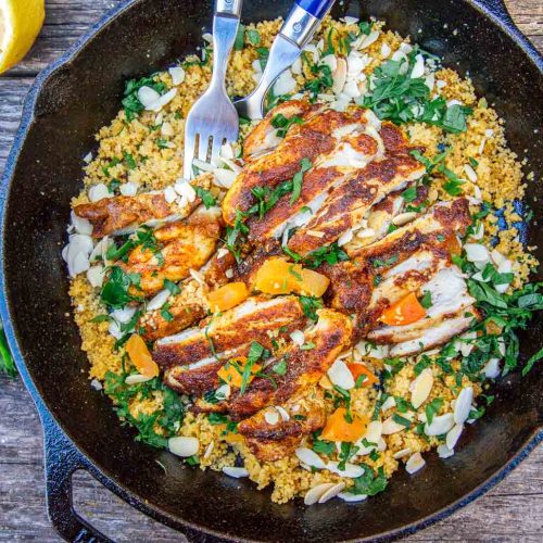 Chicken on a bed of couscous in a cast iron skillet on a camp table