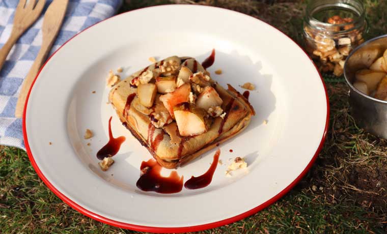 A square pancake topped with pears on a plate.