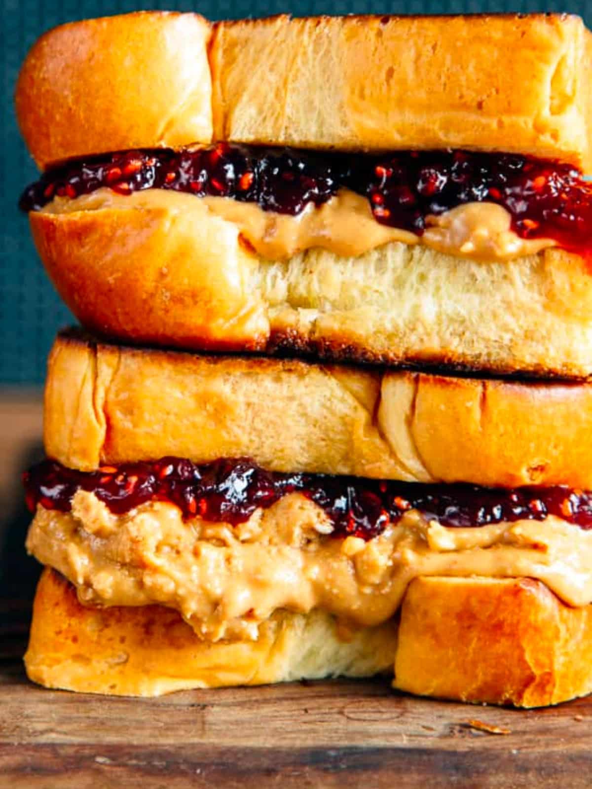 Brioche pb&j sandwich stacked on a wooden board
