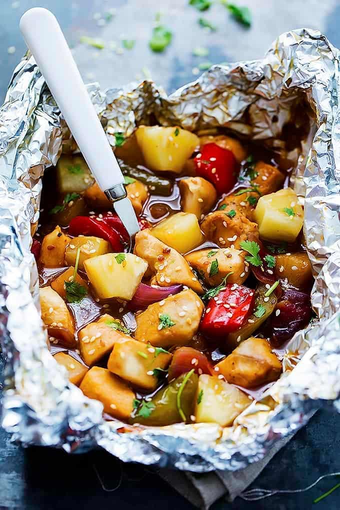 Sliced chicken, pineapple, and bell peppers in a foil packet.