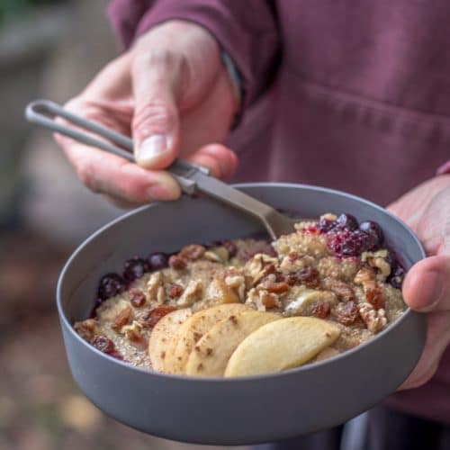 Holding a bowl of breakfast quinoa porridge with apples.