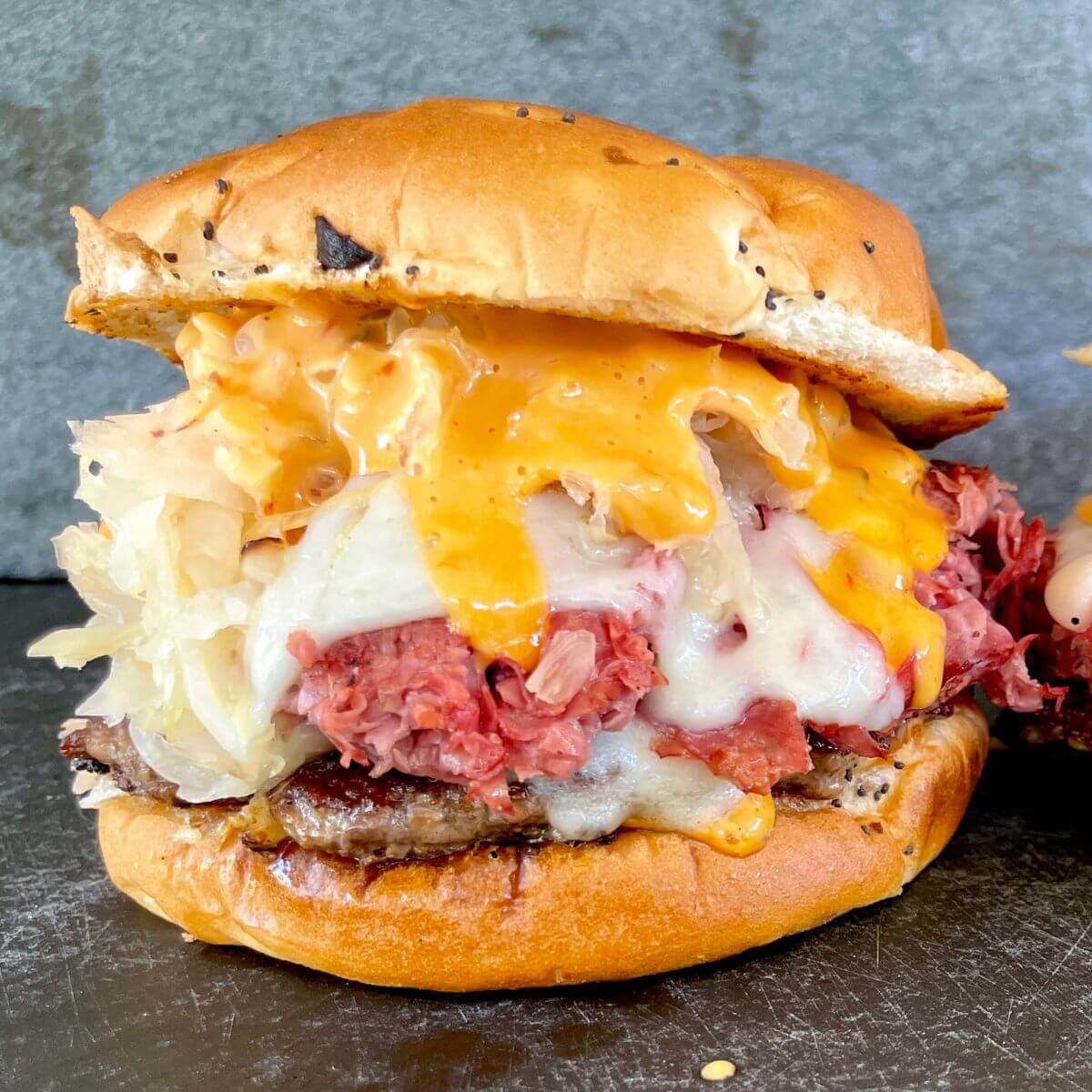 Reuben burger stacked with cheese, sauerkraut, and pastrami.