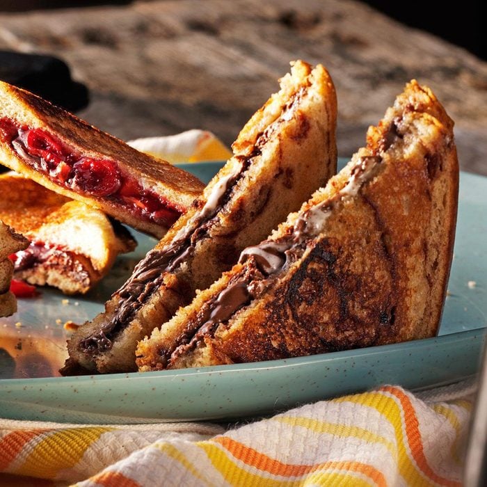 Grilled pudgy pies filled with melted chocolate on a plate.