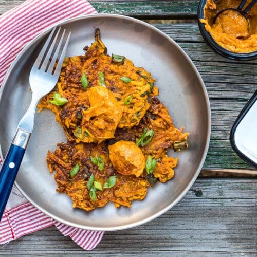 Two sweet potato fritters on a silver plate