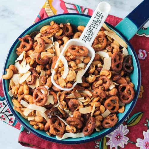 Trail mix in a blue enamel pan with a white scoop